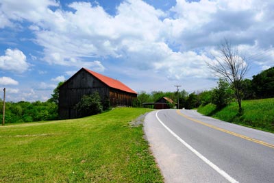 Paved highway in rural setting with a barn