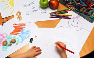 Hands of a child drawing school pictures